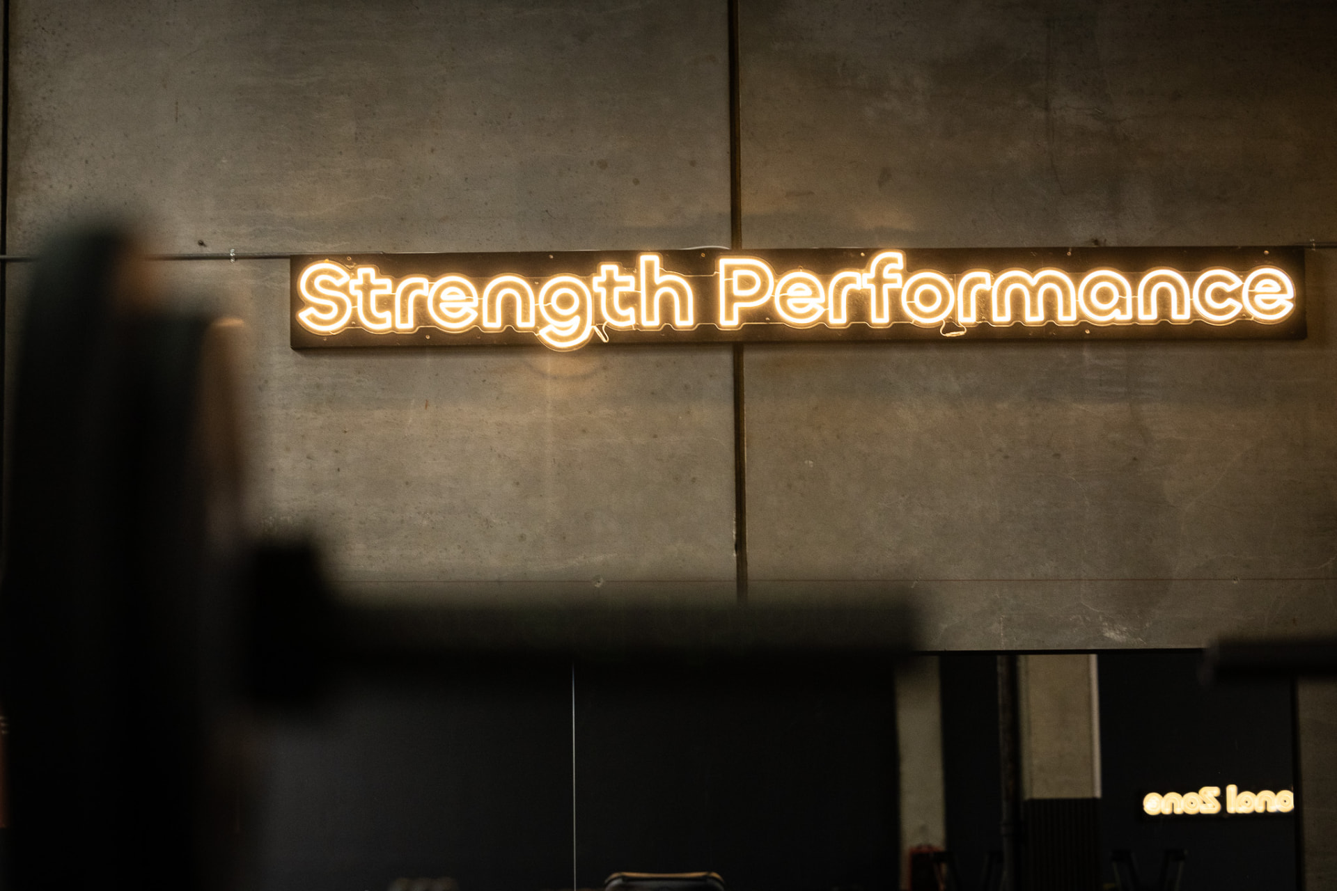 Neonskilt med teksten Strength Performance i træningscenter