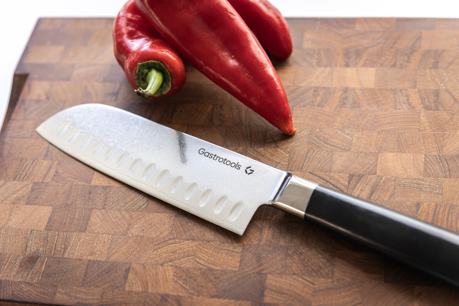 Gastrotools santokukniv på skærebræt med røde peberfrugter